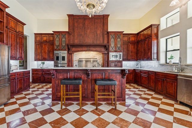 kitchen featuring sink, a center island, stainless steel appliances, decorative light fixtures, and decorative backsplash