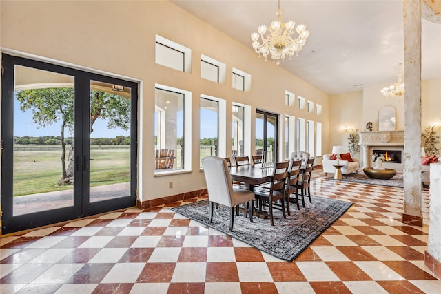 dining area with french doors, a fireplace, and an inviting chandelier