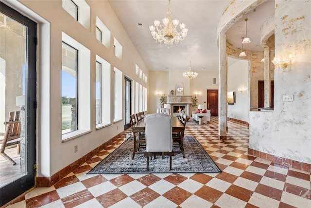 dining area with a high ceiling, a chandelier, and ornate columns