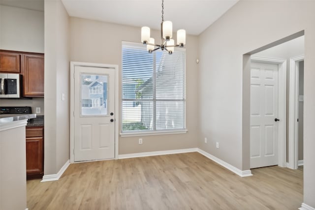 unfurnished dining area with an inviting chandelier and light wood-type flooring