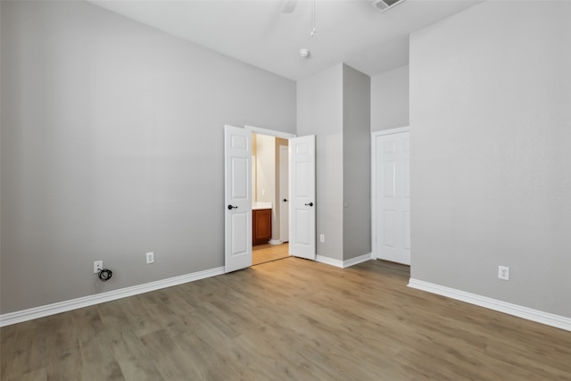 unfurnished bedroom featuring light hardwood / wood-style flooring, a towering ceiling, and ceiling fan