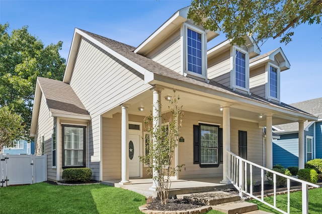 new england style home featuring a front lawn and covered porch