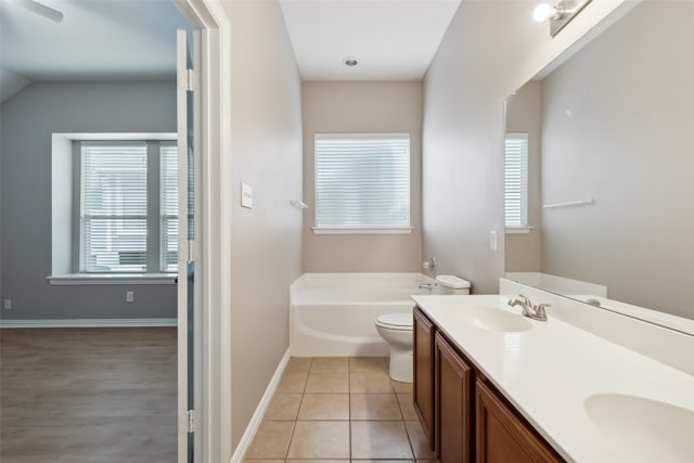 bathroom featuring toilet, vanity, a bathtub, and tile patterned flooring