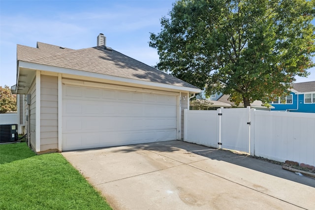 garage with central AC unit and a lawn