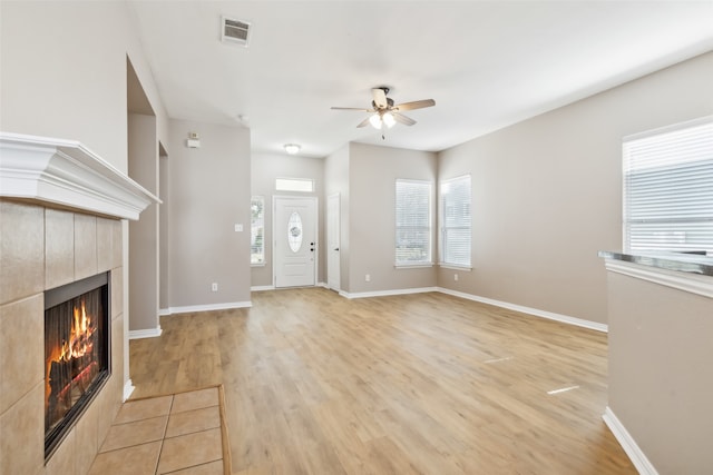 unfurnished living room with a fireplace, light wood-type flooring, and ceiling fan