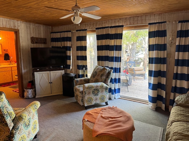 living room featuring carpet flooring, ceiling fan, wood walls, and wood ceiling