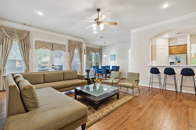 living room with ornamental molding, light hardwood / wood-style floors, and ceiling fan