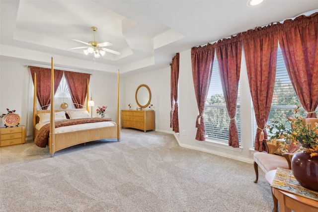 bedroom featuring light colored carpet, a raised ceiling, and ceiling fan