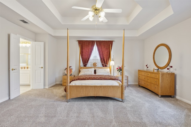 carpeted bedroom with multiple windows, a tray ceiling, and ceiling fan