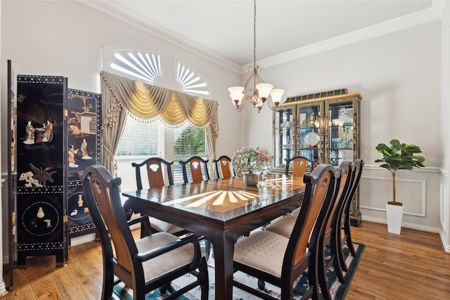 dining space with ornamental molding, a notable chandelier, and wood-type flooring