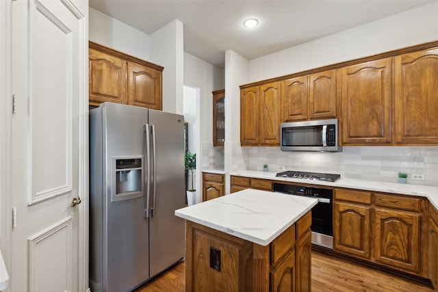 kitchen with decorative backsplash, stainless steel appliances, and light wood-type flooring