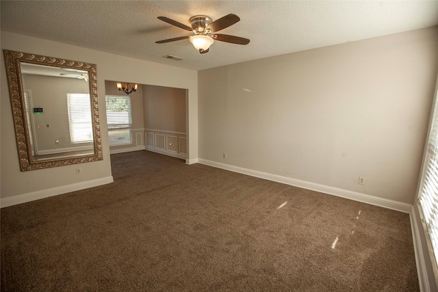 carpeted spare room featuring a textured ceiling and ceiling fan with notable chandelier