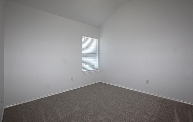 carpeted empty room featuring lofted ceiling