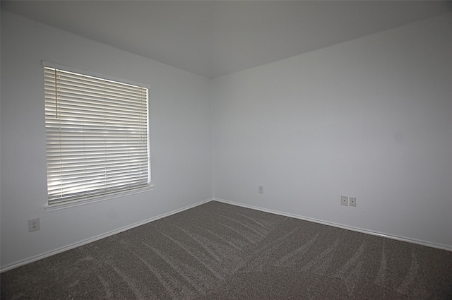 spare room featuring dark colored carpet