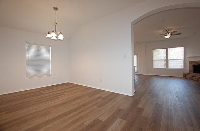 unfurnished room featuring a fireplace, lofted ceiling, ceiling fan with notable chandelier, and dark hardwood / wood-style flooring