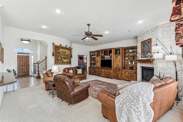 carpeted living room with ceiling fan, ornamental molding, and a fireplace