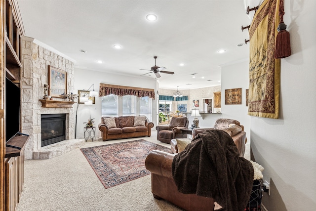 carpeted living room with ceiling fan, a stone fireplace, and ornamental molding