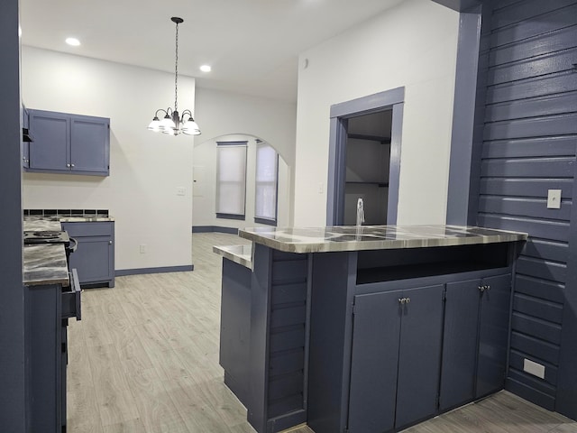 kitchen featuring kitchen peninsula, a breakfast bar, stainless steel counters, light wood-type flooring, and a notable chandelier