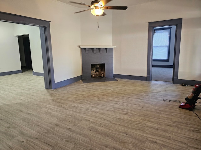 unfurnished living room featuring ceiling fan, light hardwood / wood-style flooring, and a fireplace