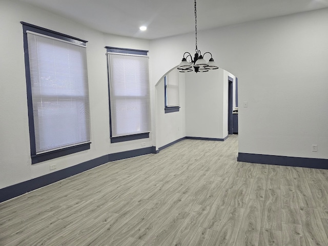 unfurnished dining area with a notable chandelier and light wood-type flooring