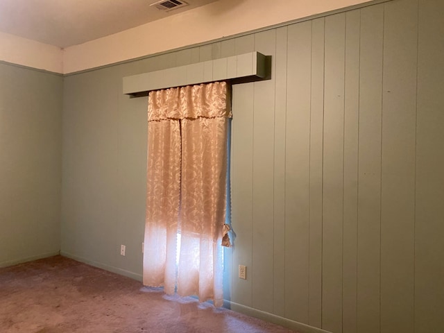 unfurnished room featuring carpet and wooden walls