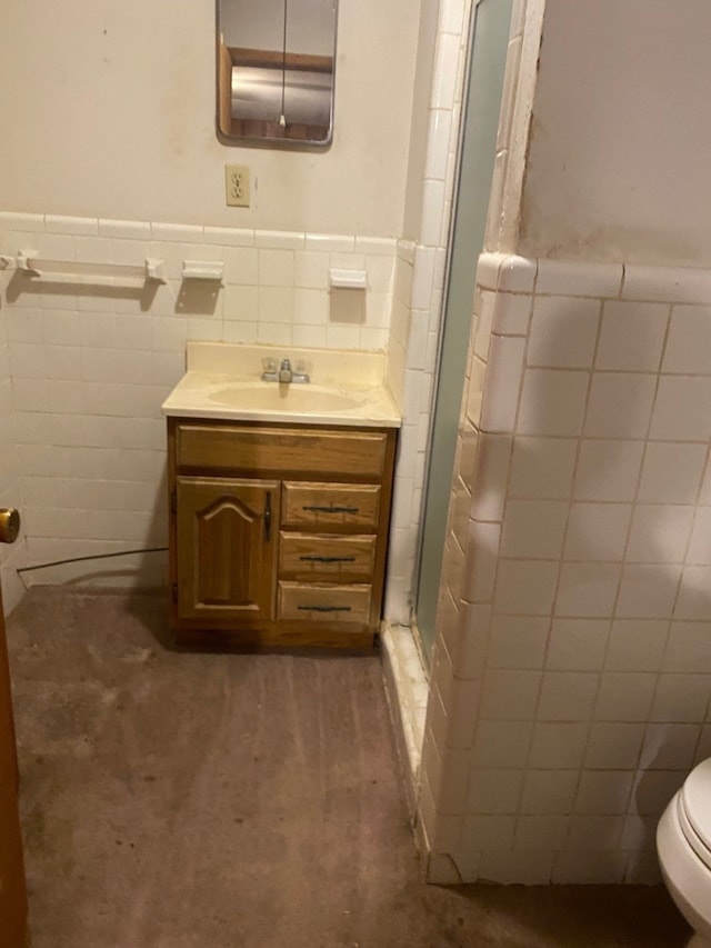 bathroom with tile walls, vanity, toilet, and walk in shower