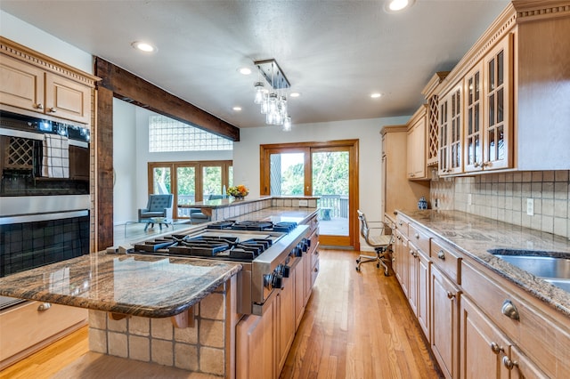 kitchen with a kitchen bar, stainless steel gas cooktop, a center island, light hardwood / wood-style floors, and decorative backsplash