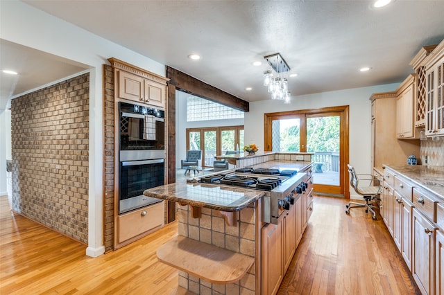 kitchen featuring appliances with stainless steel finishes, french doors, a center island, a kitchen breakfast bar, and light hardwood / wood-style flooring