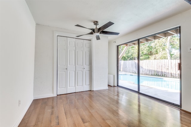 unfurnished bedroom featuring a closet, access to outside, light hardwood / wood-style flooring, a textured ceiling, and ceiling fan