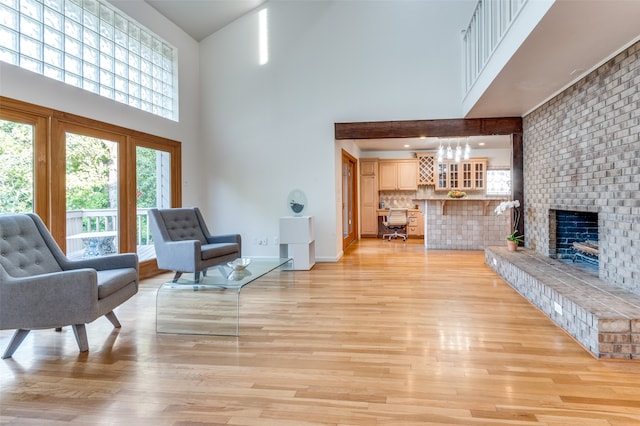 living room with a towering ceiling, a fireplace, and light wood-type flooring