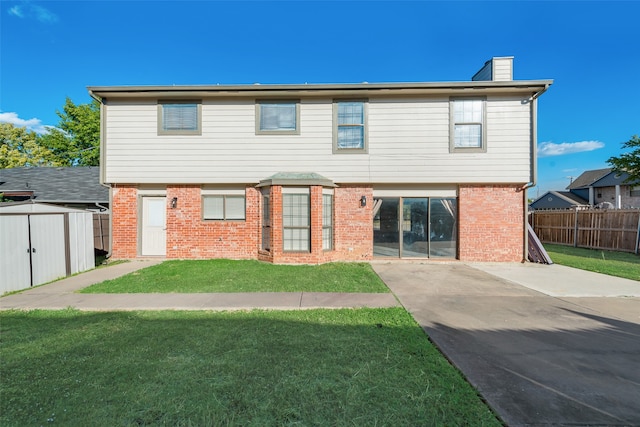 rear view of property with a storage unit, a yard, and a patio area