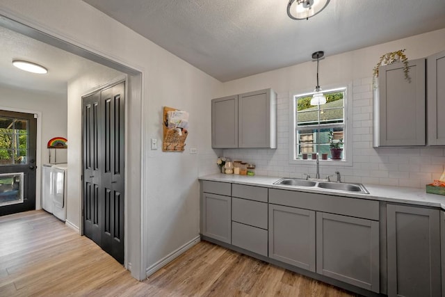 504 E Monterey St, Denison, TX 75021 - kitchen with light wood-style flooring, a sink, backsplash, gray cabinetry, and washer and dryer
