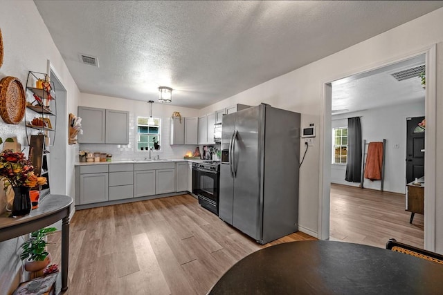 504 E Monterey St, Denison, TX 75021 - kitchen featuring black gas range oven, stainless steel fridge with ice dispenser, visible vents, gray cabinets, and a textured ceiling
