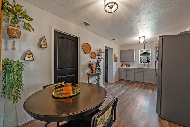 dining area with sink, a textured ceiling, and light wood-type flooring