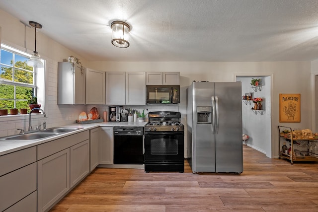 kitchen with sink, black appliances, gray cabinetry, and light hardwood / wood-style floors