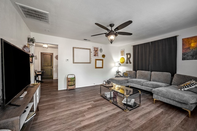 living room with a textured ceiling, dark hardwood / wood-style floors, and ceiling fan