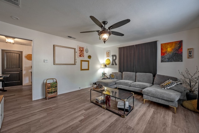 living room featuring hardwood / wood-style floors, a textured ceiling, and ceiling fan