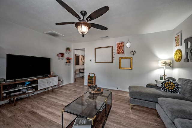 living room featuring a textured ceiling, hardwood / wood-style flooring, and ceiling fan