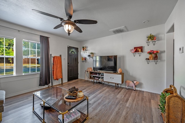 living room with light hardwood / wood-style floors, a textured ceiling, and ceiling fan