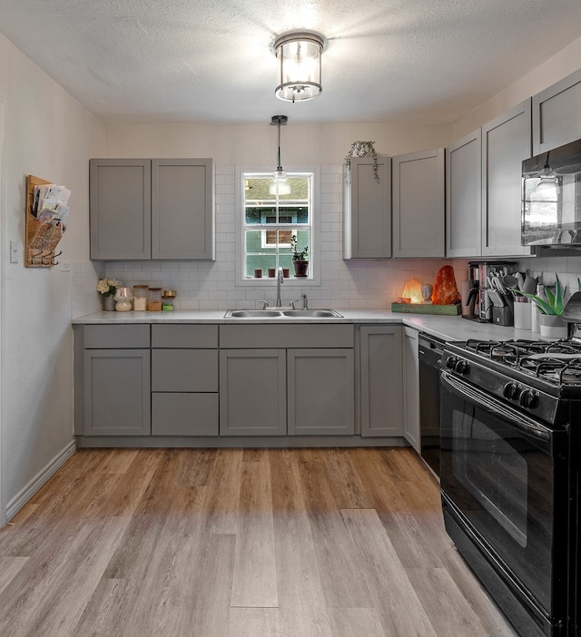 kitchen with sink, black appliances, light hardwood / wood-style flooring, and gray cabinetry