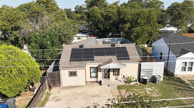 back of property with solar panels and a lawn