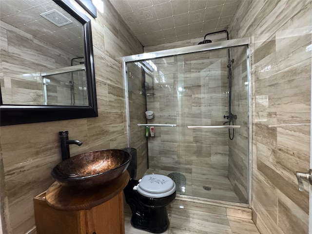 bathroom featuring vanity, a shower with shower door, toilet, and tile walls