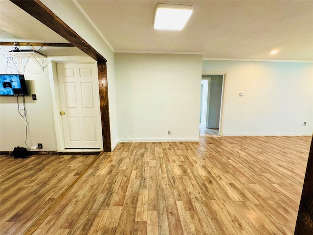 basement with light hardwood / wood-style flooring and crown molding