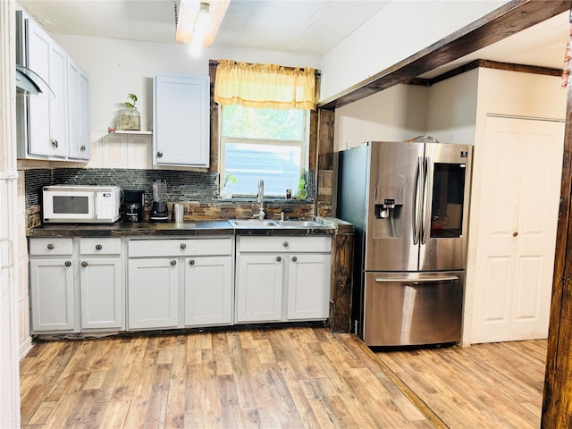 kitchen with white cabinetry, tasteful backsplash, light wood-type flooring, and stainless steel fridge