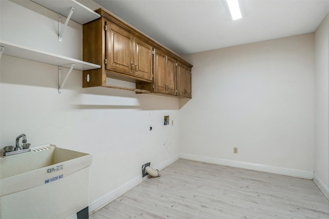 clothes washing area with sink, washer hookup, light wood-type flooring, and cabinets