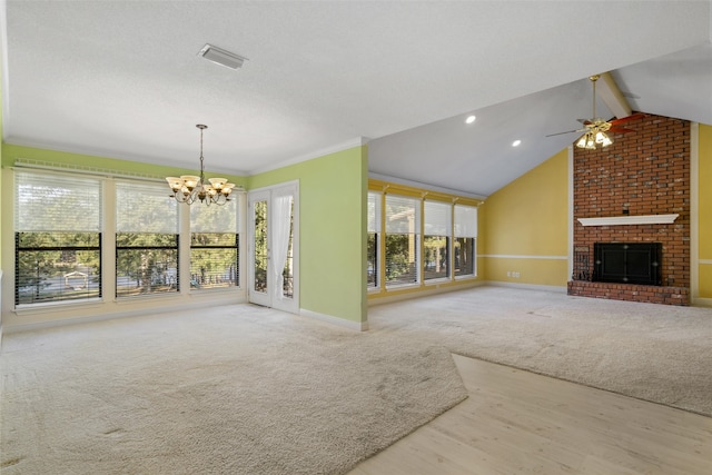 unfurnished living room featuring vaulted ceiling with beams, ceiling fan with notable chandelier, a brick fireplace, light carpet, and ornamental molding