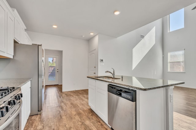 kitchen with sink, appliances with stainless steel finishes, white cabinets, and an island with sink