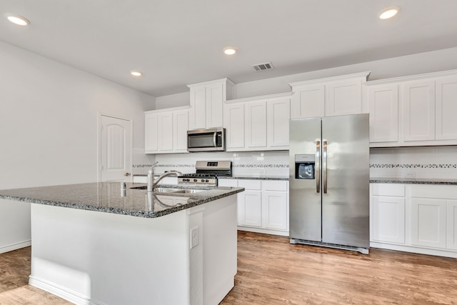 kitchen with an island with sink, stainless steel appliances, light hardwood / wood-style floors, and white cabinetry