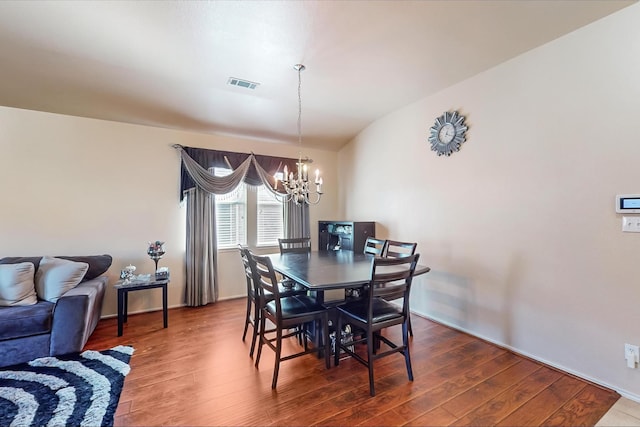 dining space featuring lofted ceiling, hardwood / wood-style flooring, and a chandelier