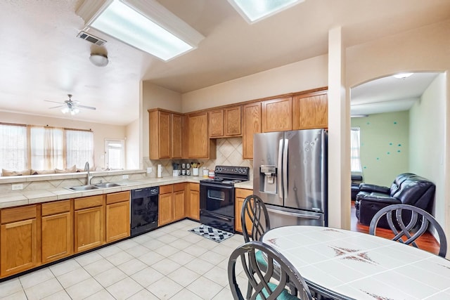 kitchen with decorative backsplash, tile countertops, sink, black appliances, and ceiling fan